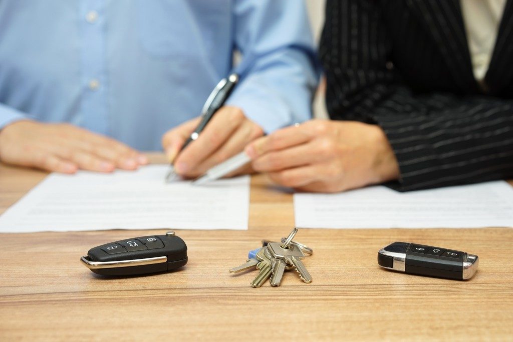 two people signing auto papers
