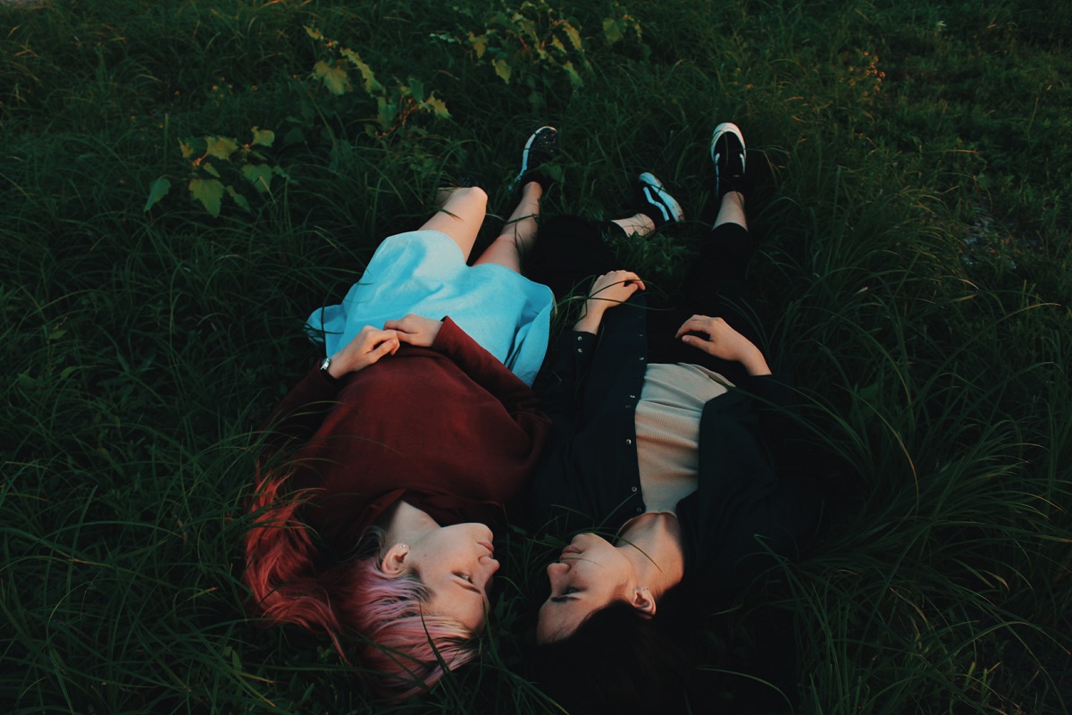 two women laying on grass